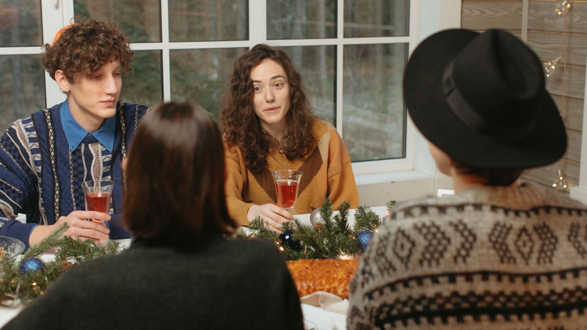 A group of friends enjoying a festive holiday meal with drinks and decorations.