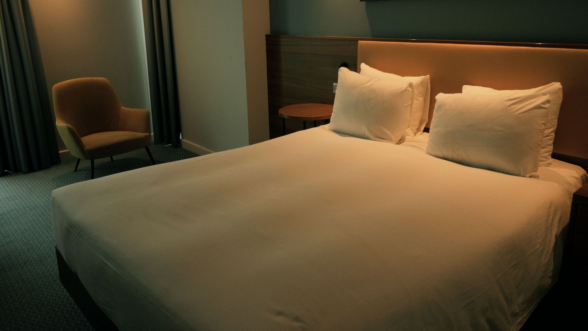 Warm-toned hotel room with a large bed and minimalist decor