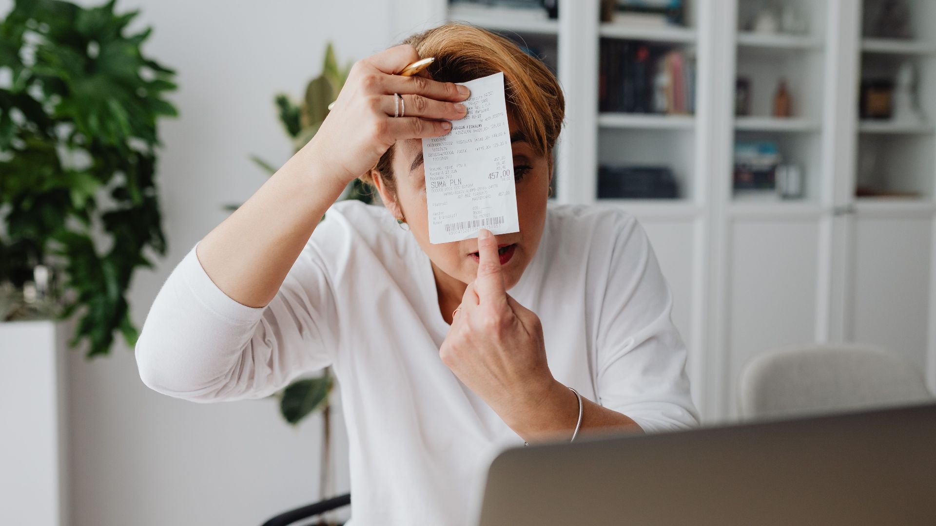 Businesswoman showing a receipt during a home office work session, highlighting technology integration.