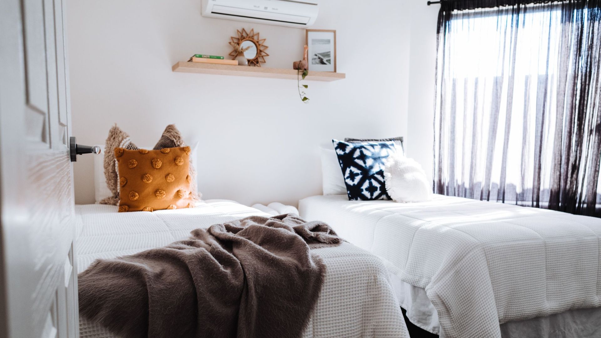 Interior of comfortable bedroom with soft beds covered with white pillows with cushions near window