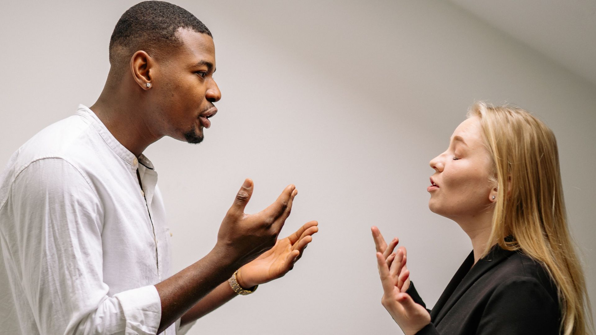 A couple engaged in a heated argument indoors, expressing strong emotions and gestures.