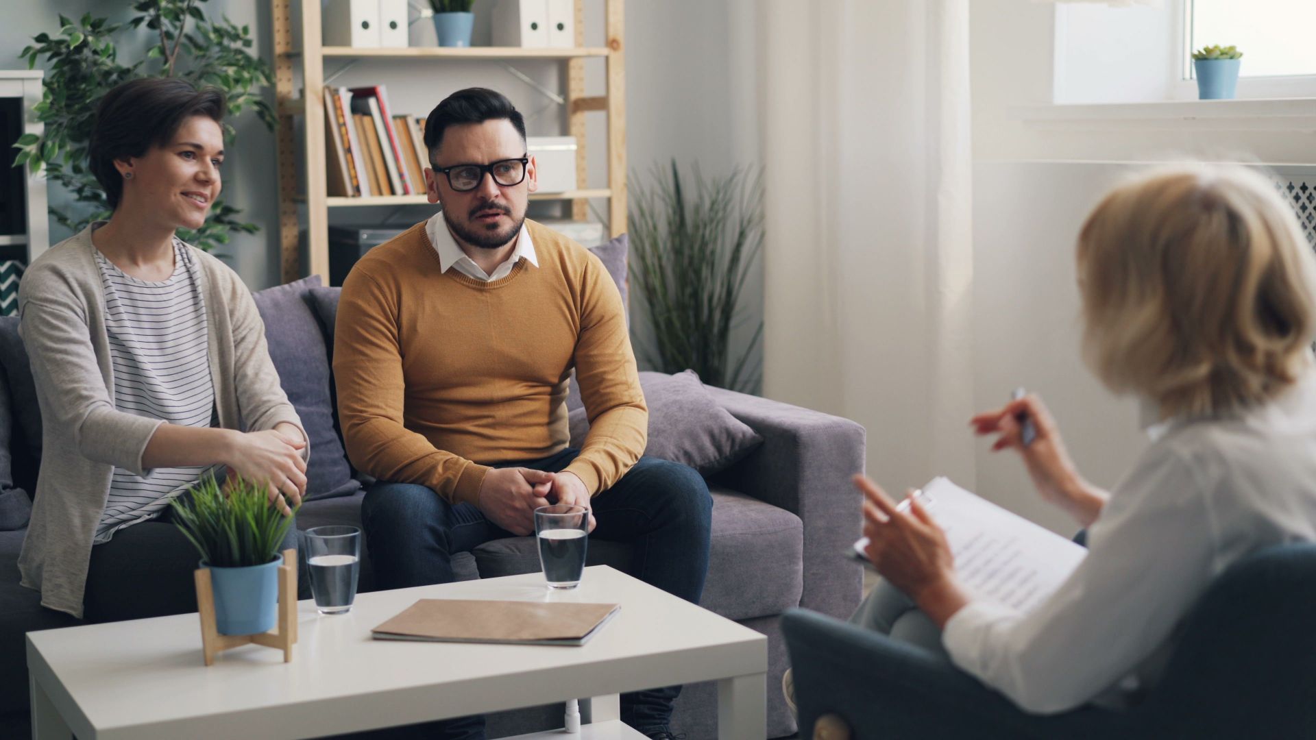 Couple discussing issues with therapist during a counseling session in a cozy office.