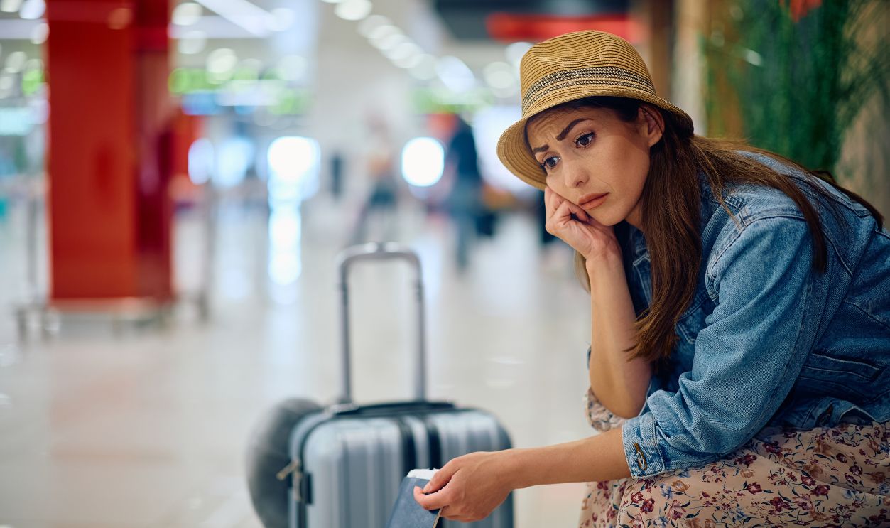 Shutterstock - 2464429807 - Distraught female passenger waiting at departure area.