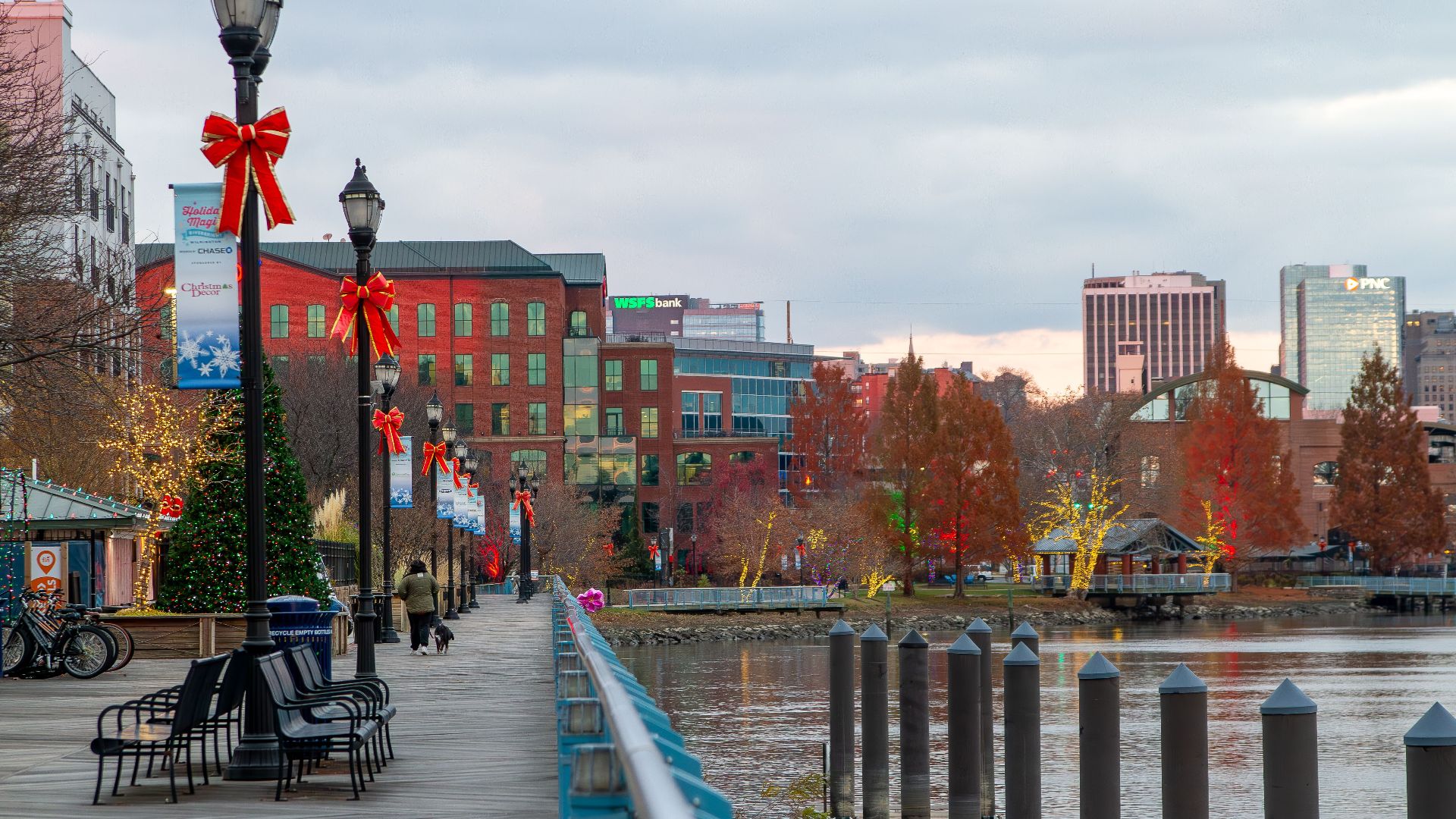 Festively decorated Wilmington riverfront with holiday lights and bows along the walkway.