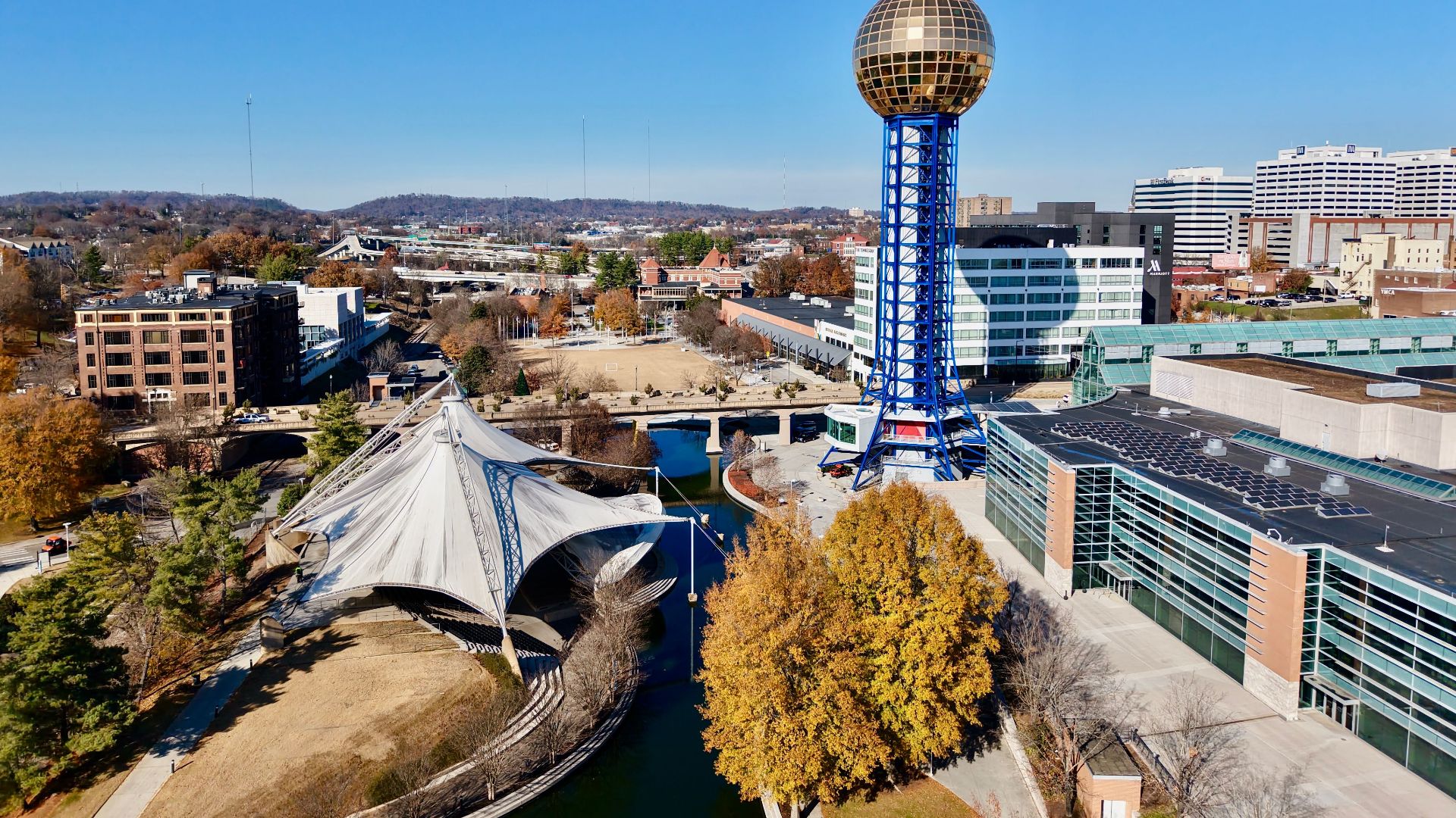 Drone view of the Sunsphere at World's Fair Park, Knoxville, showcasing modern architecture and fall foliage.