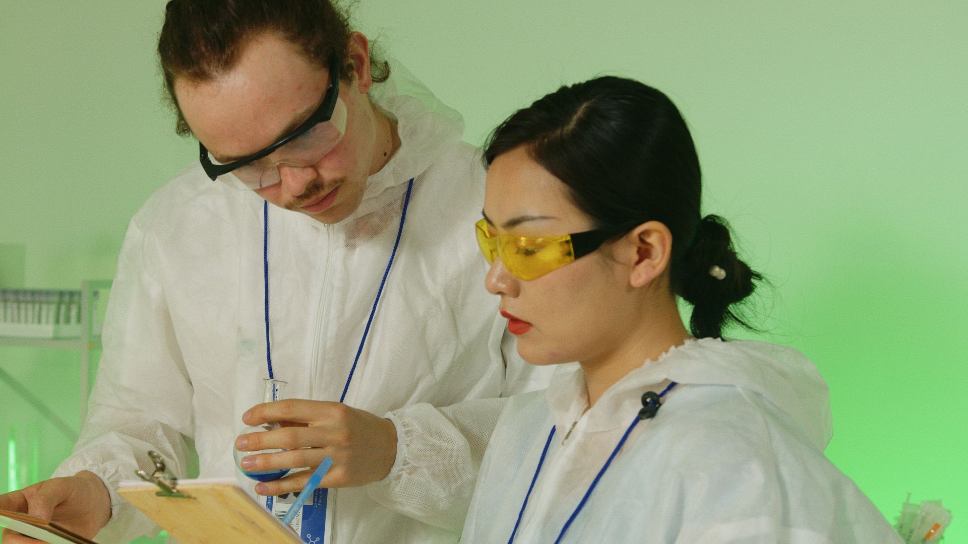 Two scientists in protective gear discussing research findings in a laboratory.