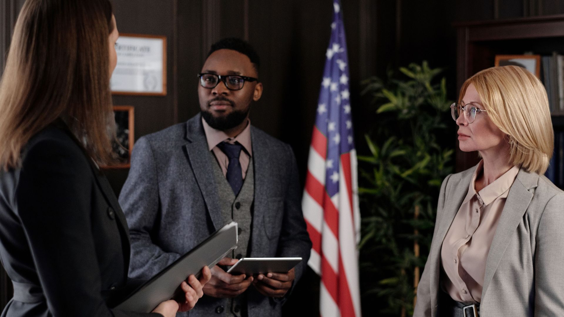 A group of business professionals discussing in an office with a USA flag.