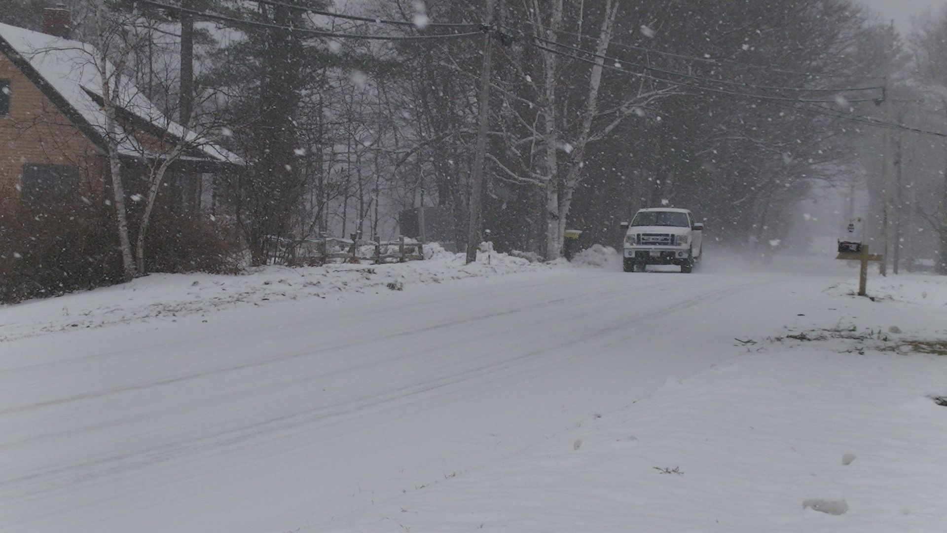 Truck drives through snow on road in Bryant Pond, Maine