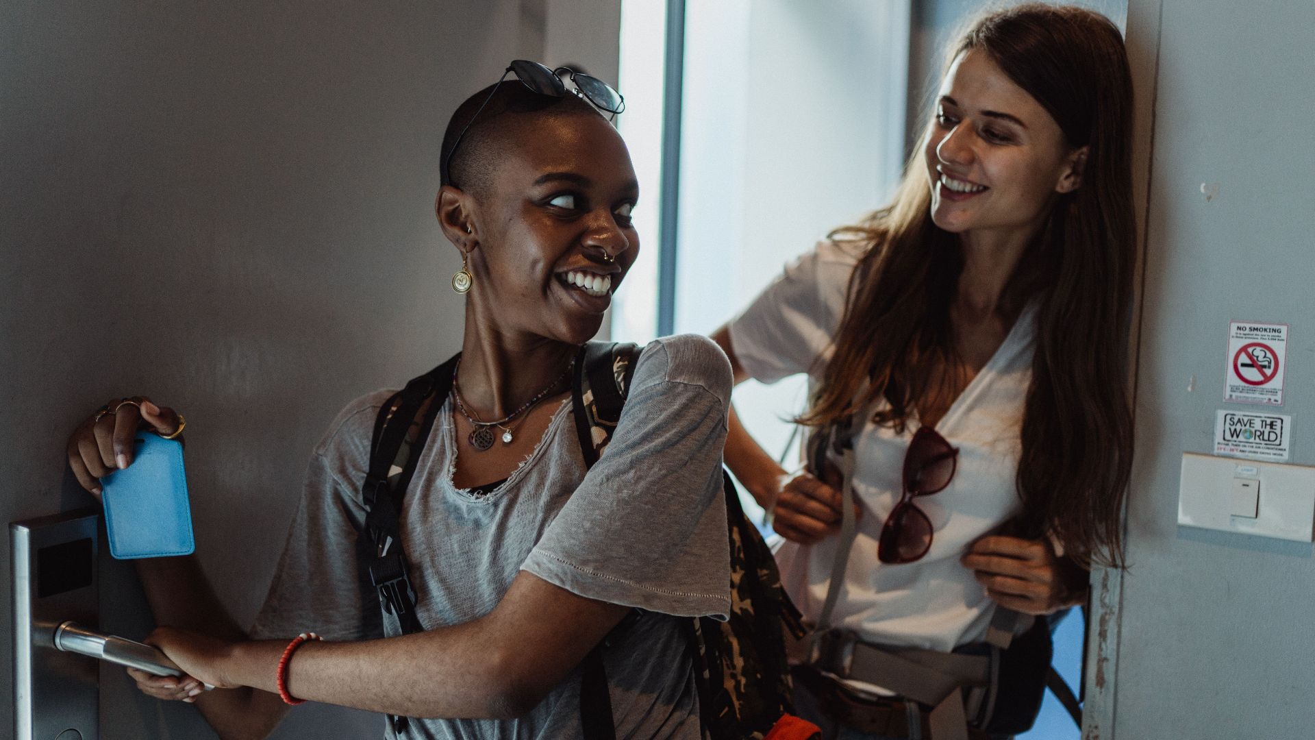 Two women smiling as they enter a room using a key card, representing a positive travel experience.