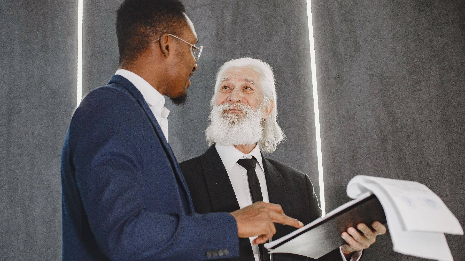 Two businessmen discussing documents in a modern office setting, highlighting professional diversity.