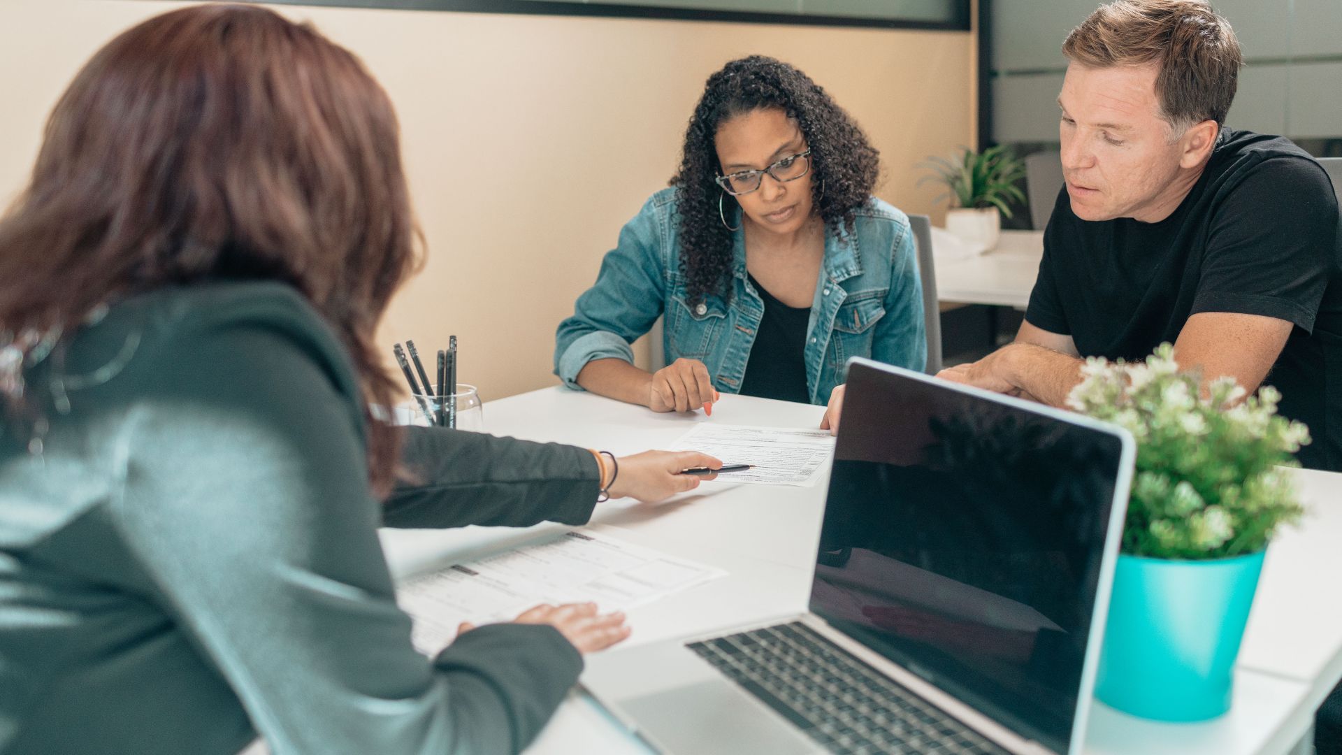 Couple meeting with advisor for adoption process in a modern office setting.
