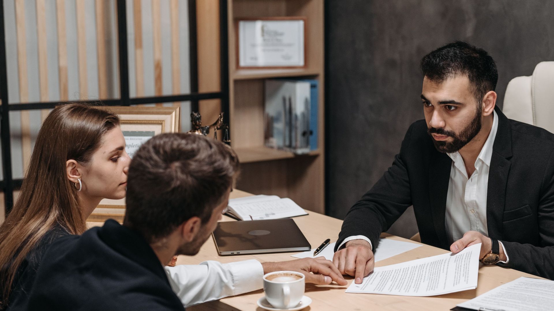Lawyer discussing legal documents with clients at office desk.