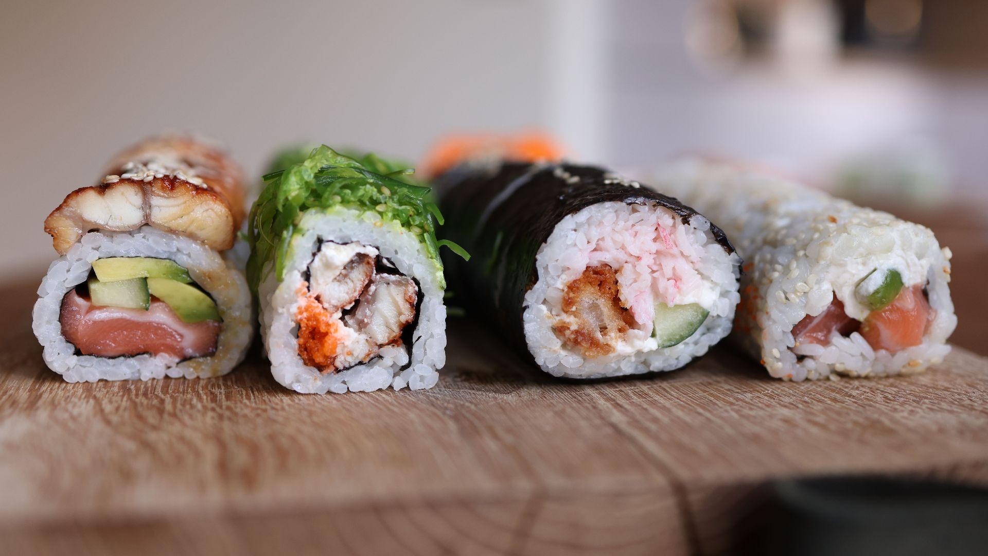 Close-up of assorted sushi rolls on a wooden board showcasing fresh ingredients.