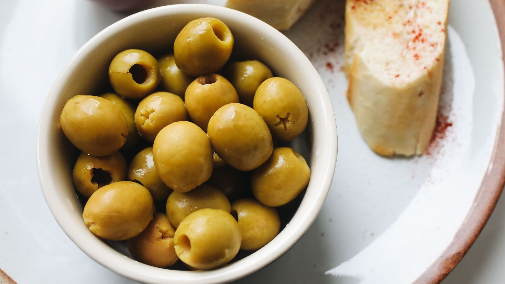A delicious serving of green olives and sliced bread, perfect for a light snack.