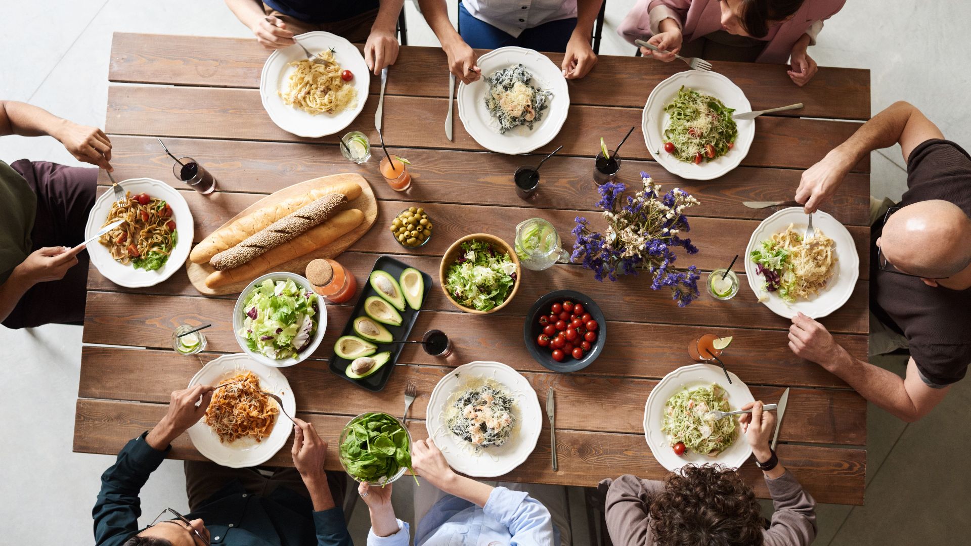 A diverse group of adults enjoying a shared meal indoors, viewed from above.