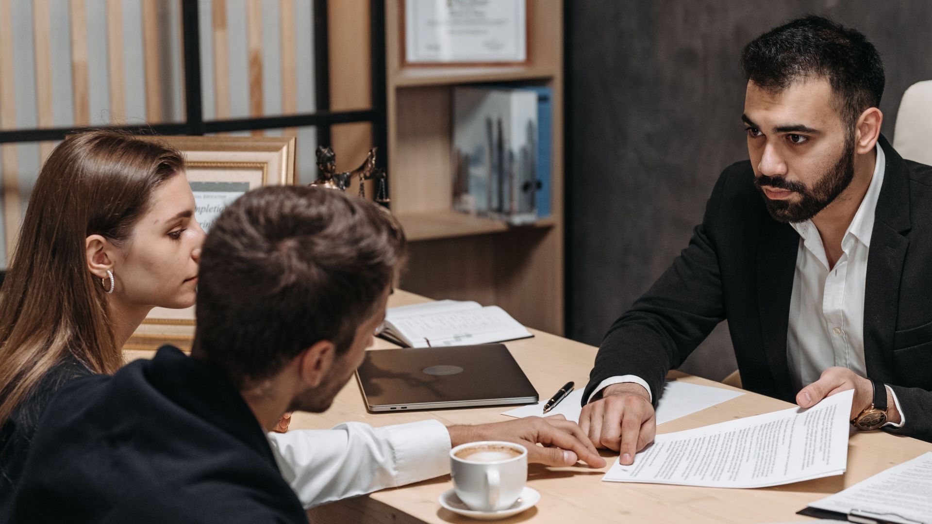 Lawyer discussing legal documents with clients at office desk.