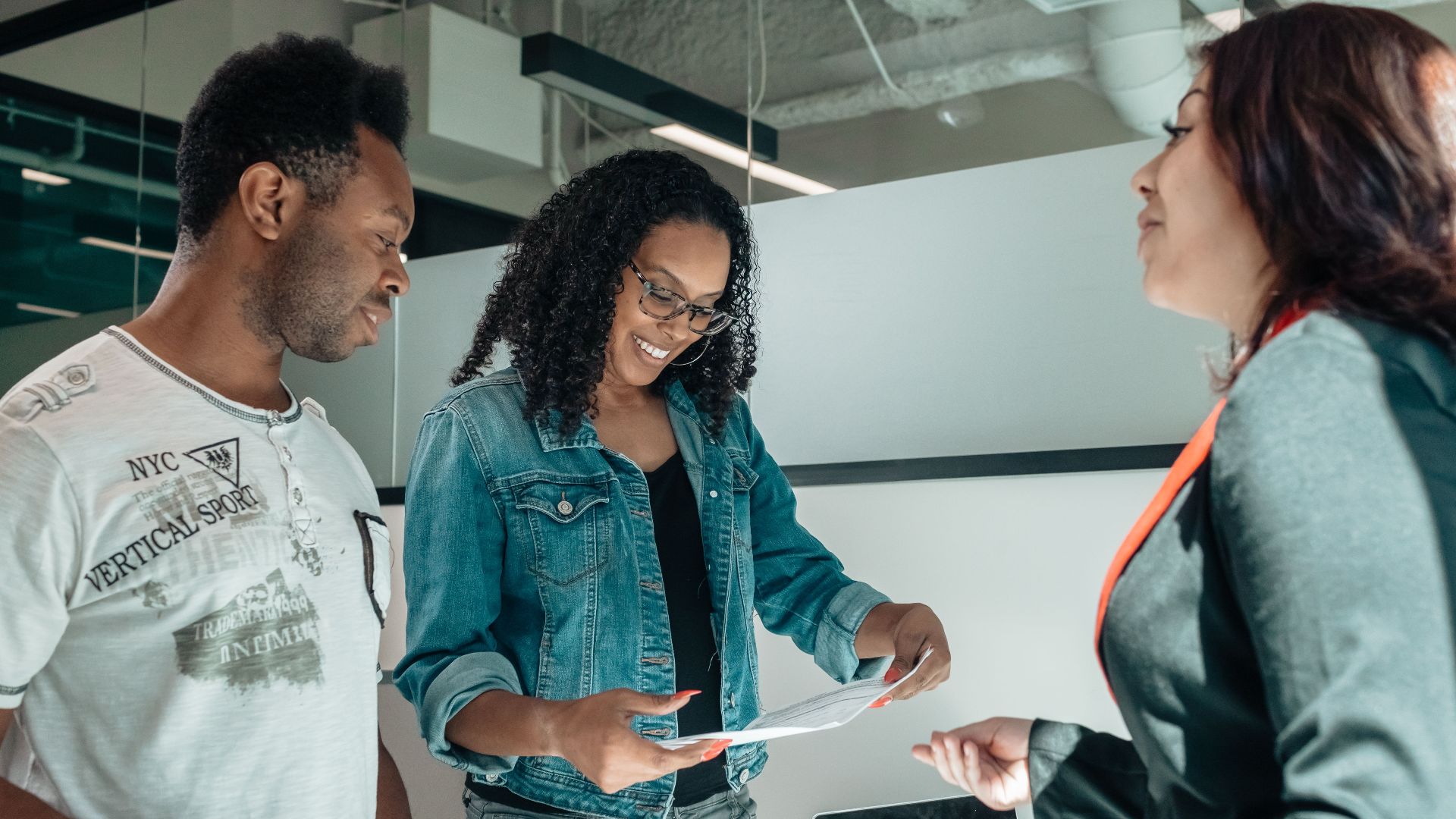 Three adults engaging in a business discussion in a bright, modern office setting.