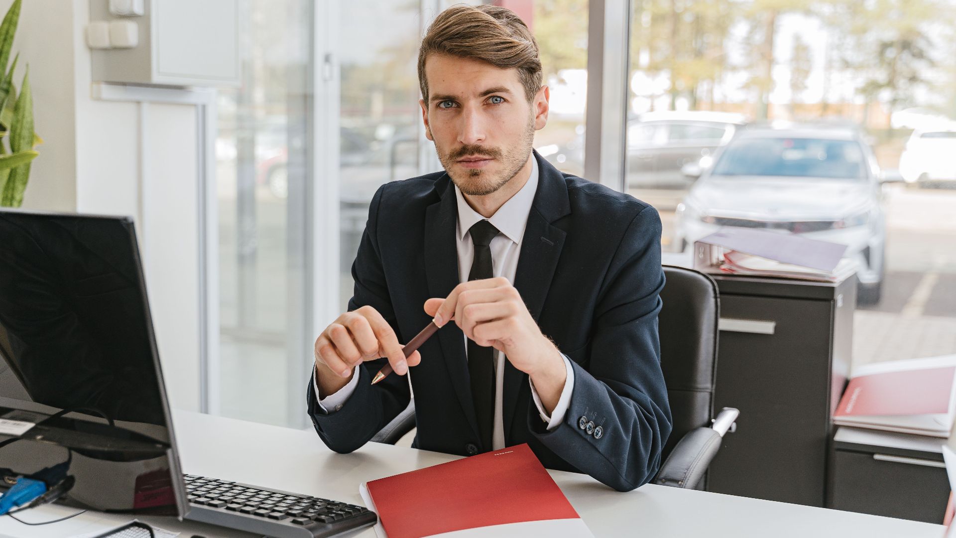 Business professional sitting at a desk with documents in an office environment.