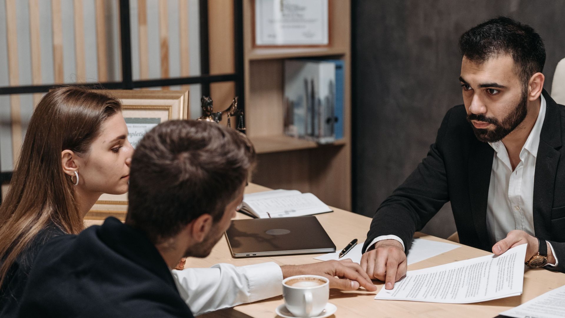 Lawyer discussing legal documents with clients at office desk.