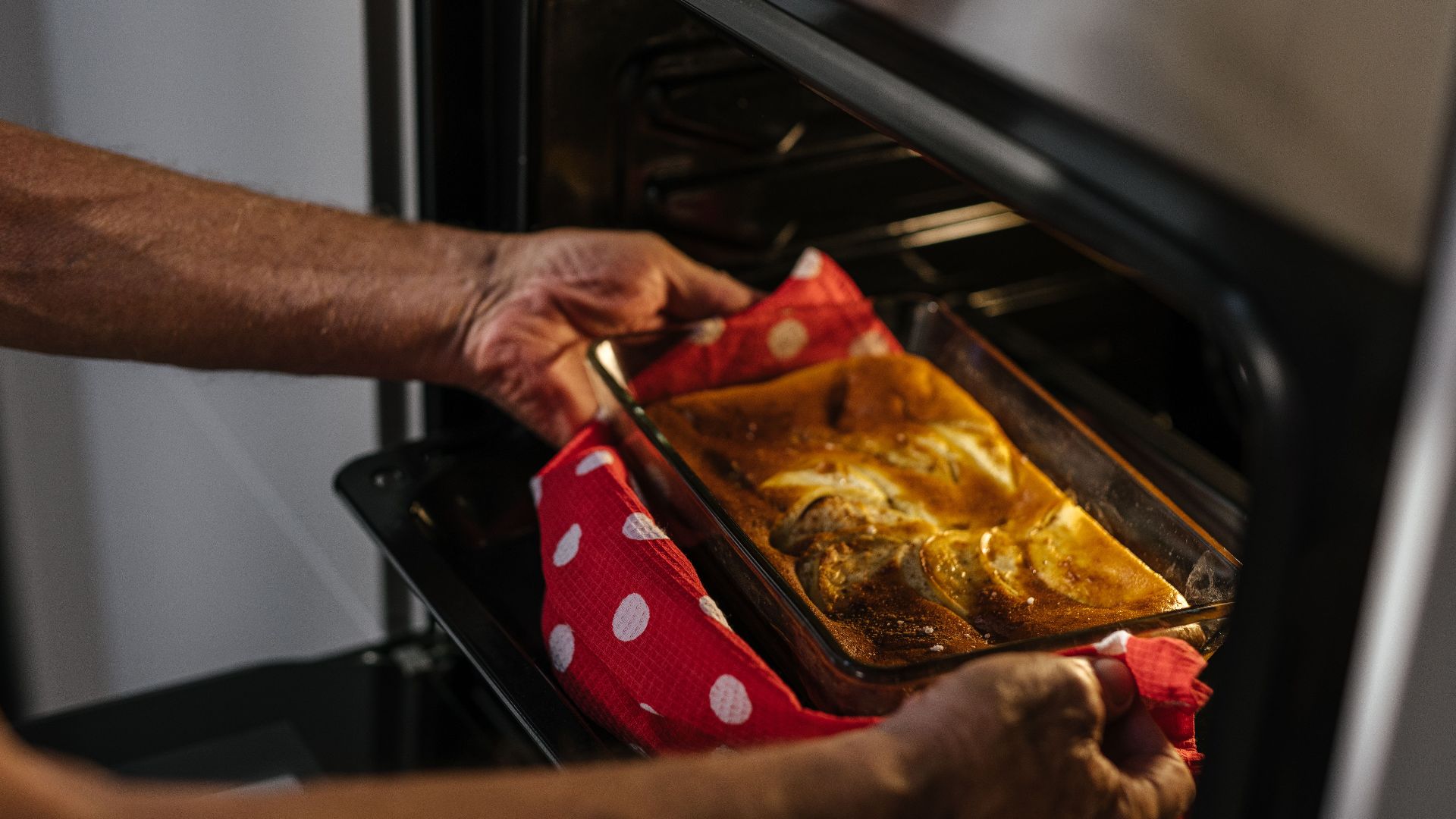 Person removes freshly baked cake from oven, showcasing home baking joy.