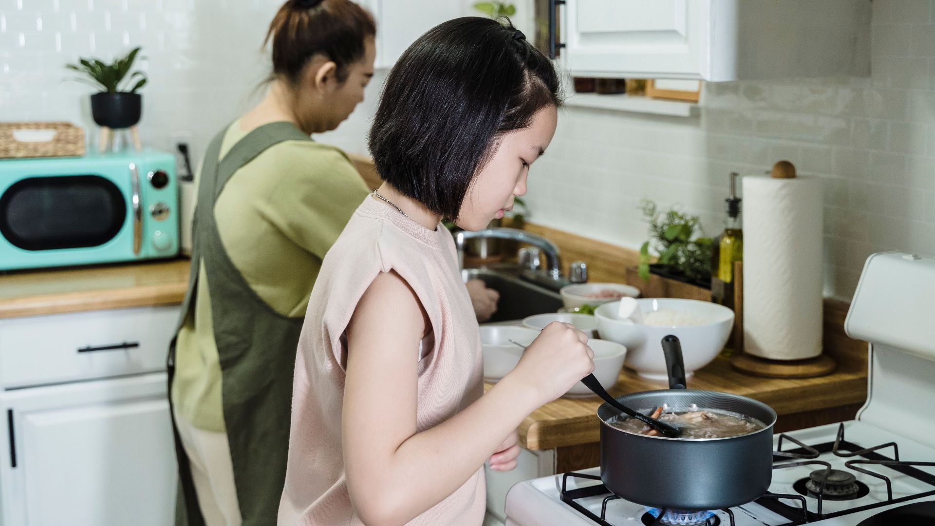 A mother and daughter preparing food together, focusing on family and teamwork in the kitchen.