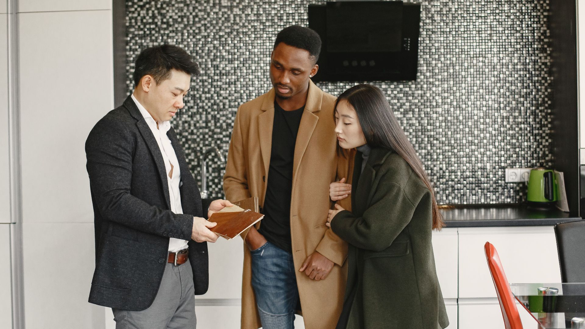 A business meeting in a contemporary kitchen showing diverse professionals discussing strategic options.