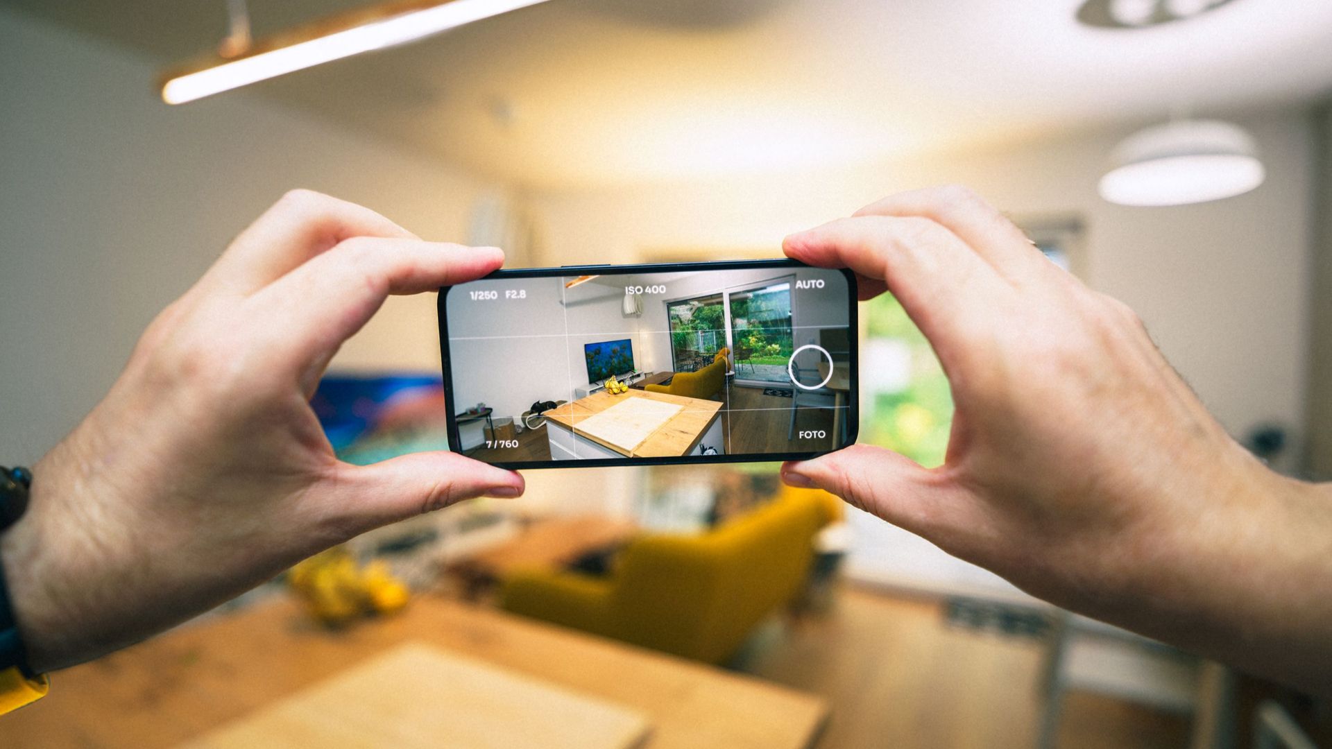 Hands capturing a modern living room interior with a smartphone.