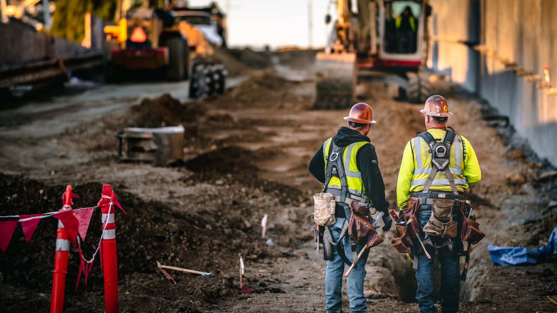 Construction photographer Daniel Mekis captured two workers looking out at a project where they were building a wall and roadway.  The construction site photo shows details of a project in progress and under construction.