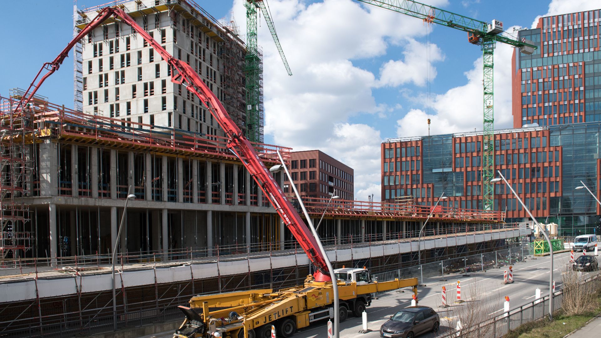 Busy construction site in Hamburg with cranes and trucks under a clear sky.
