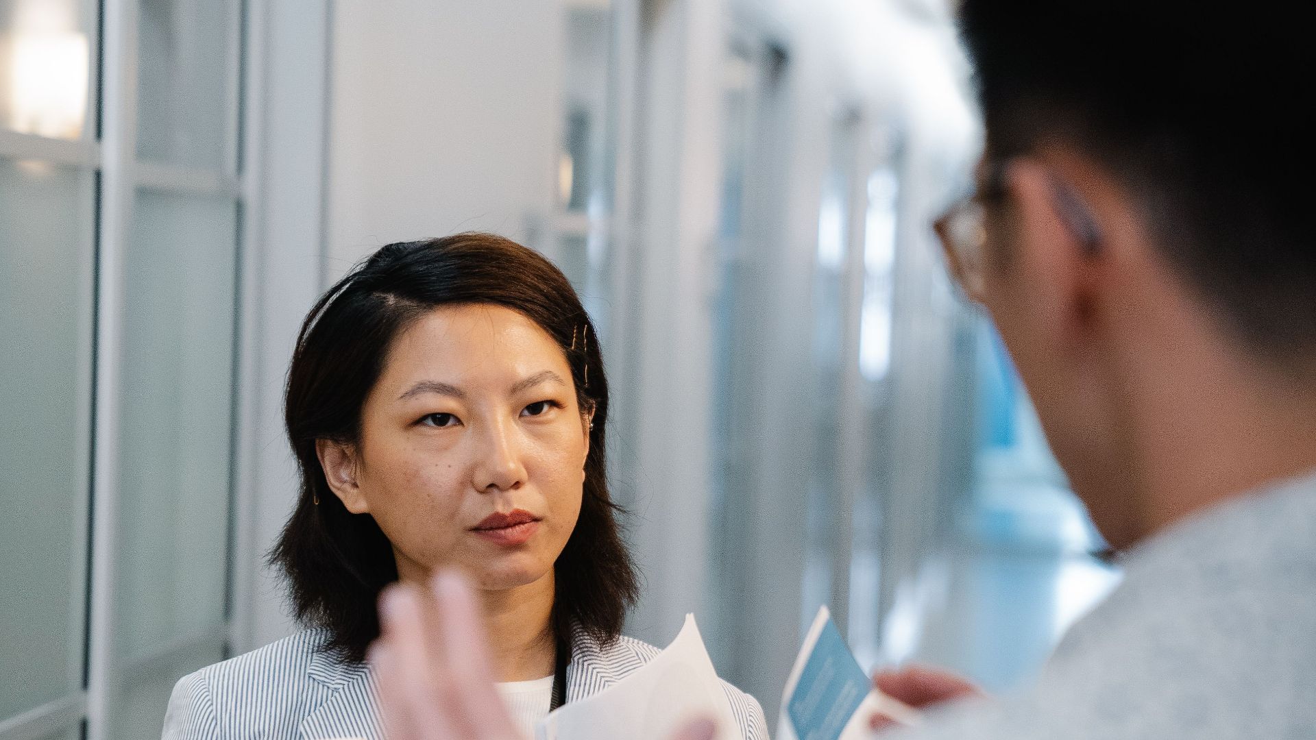A man and woman having a conversation in a modern office hallway.