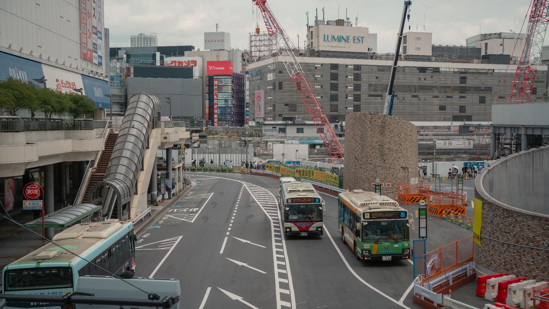 Street view in Tokyo with buses, cranes, and modern buildings. Urban life in Japan.