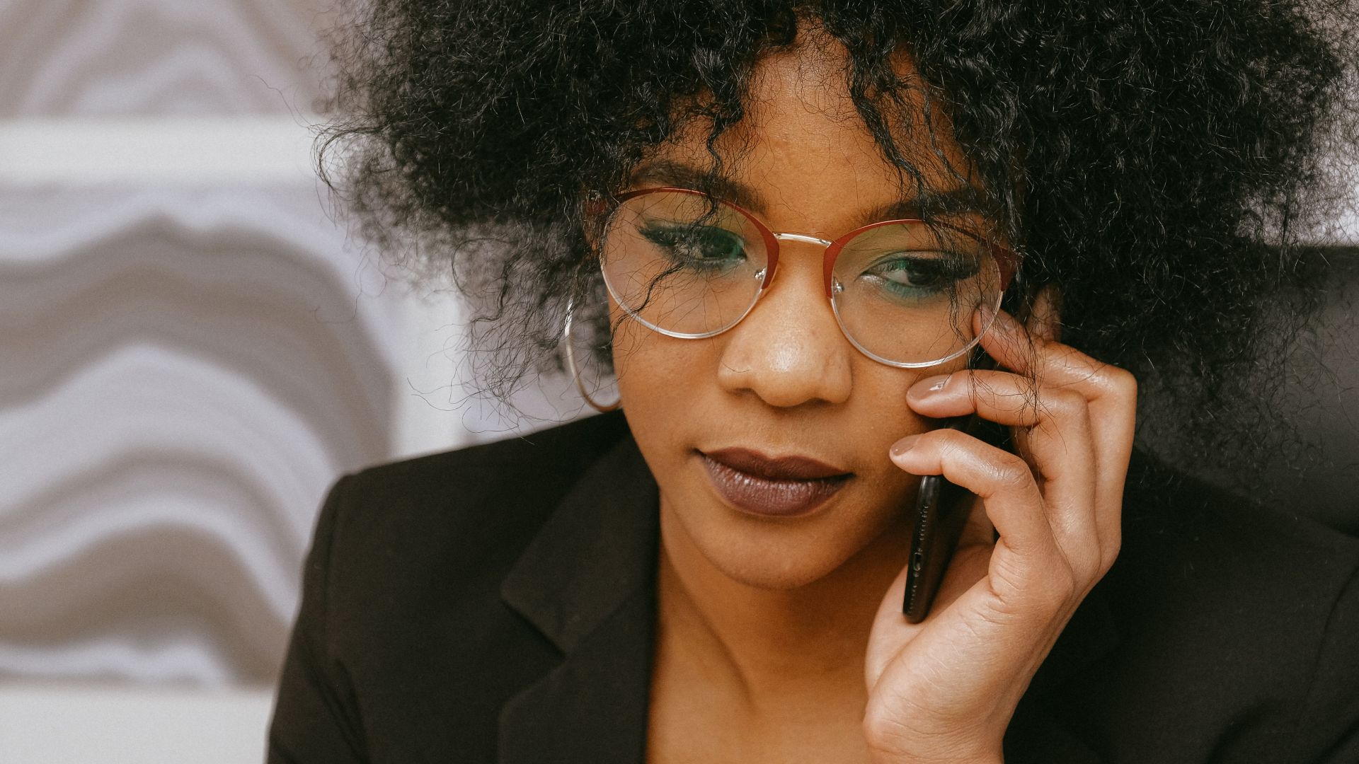 African American businesswoman in office, focused on phone call and tasks.