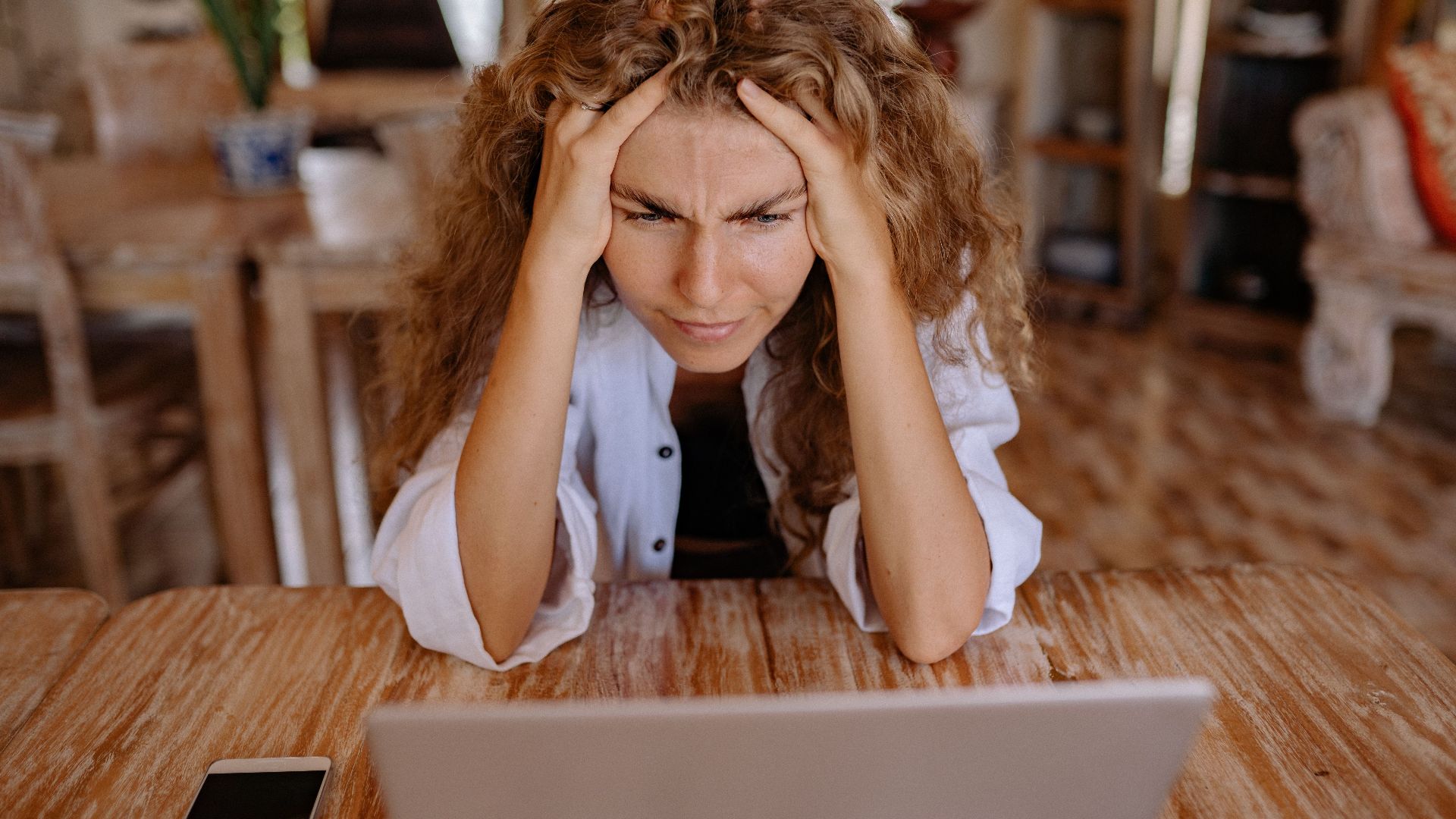 Stressed woman at home struggling with remote work on her laptop.