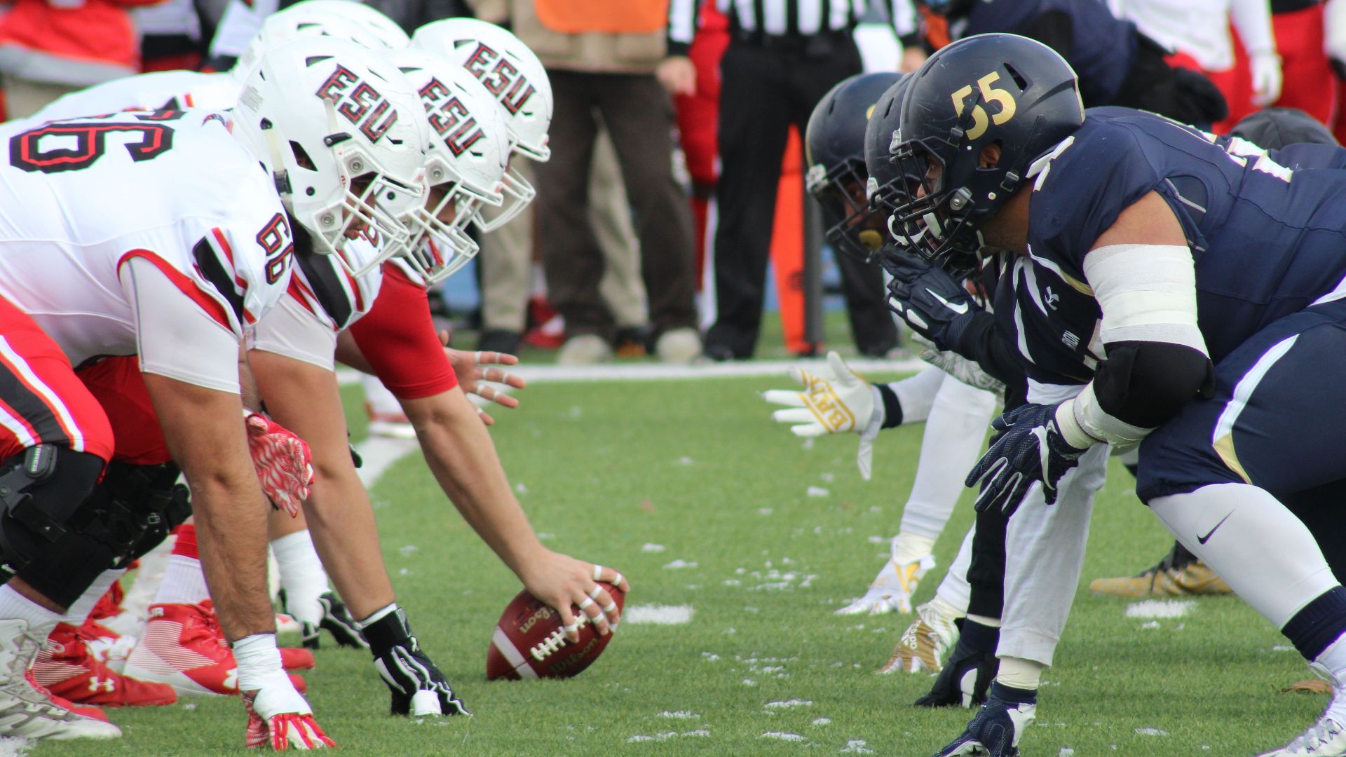 Rival football teams face off at the start of an action-packed game on the field.