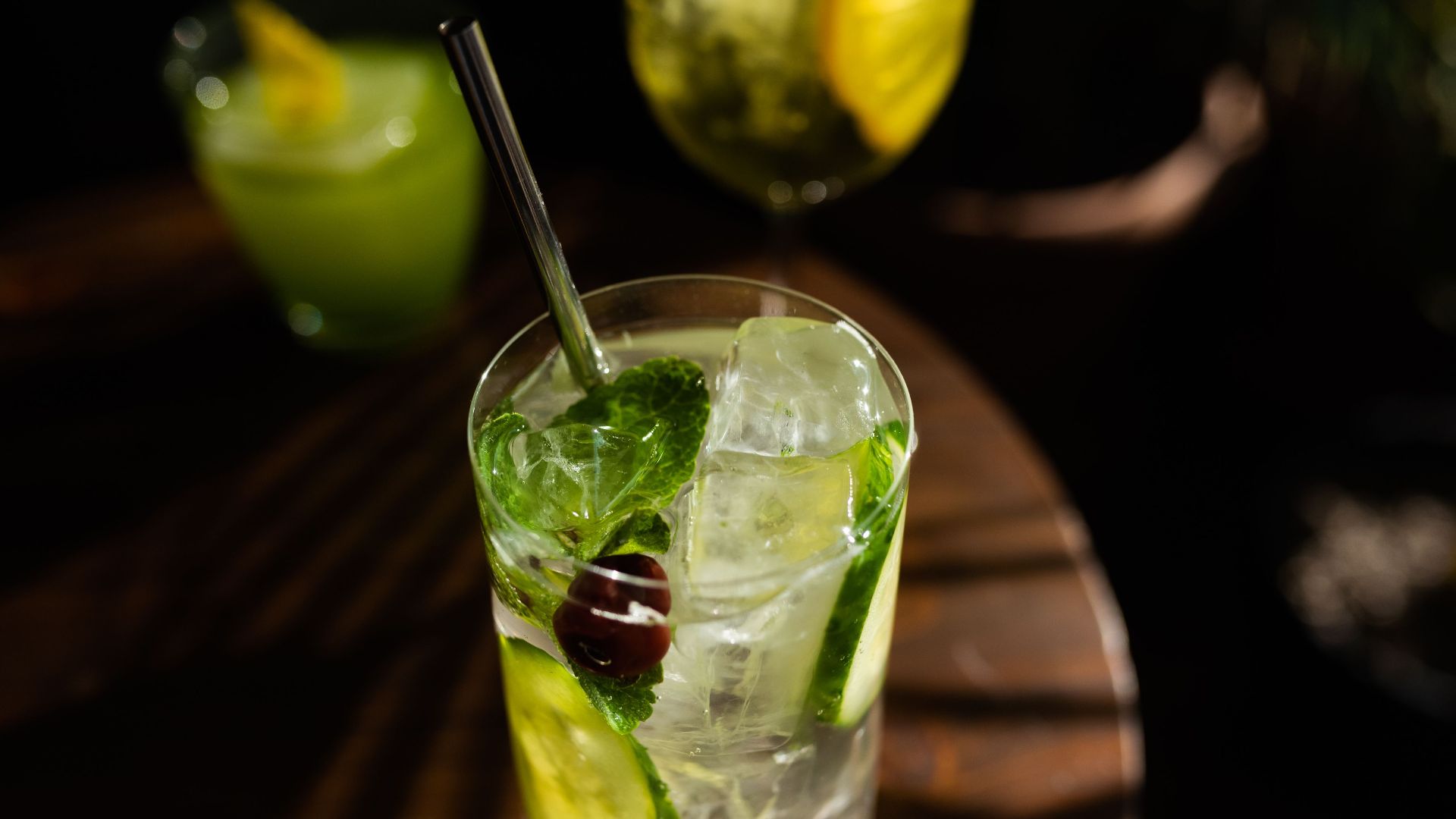 Close-up of a refreshing cocktail with mint, lime, and ice in a glass with a metallic straw.