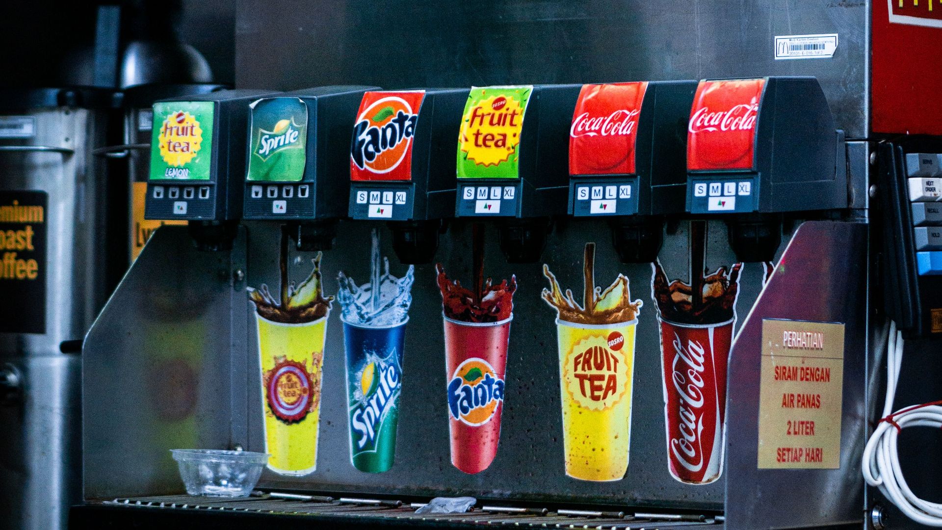 Soft drink dispenser with various soda options in fast food restaurant.