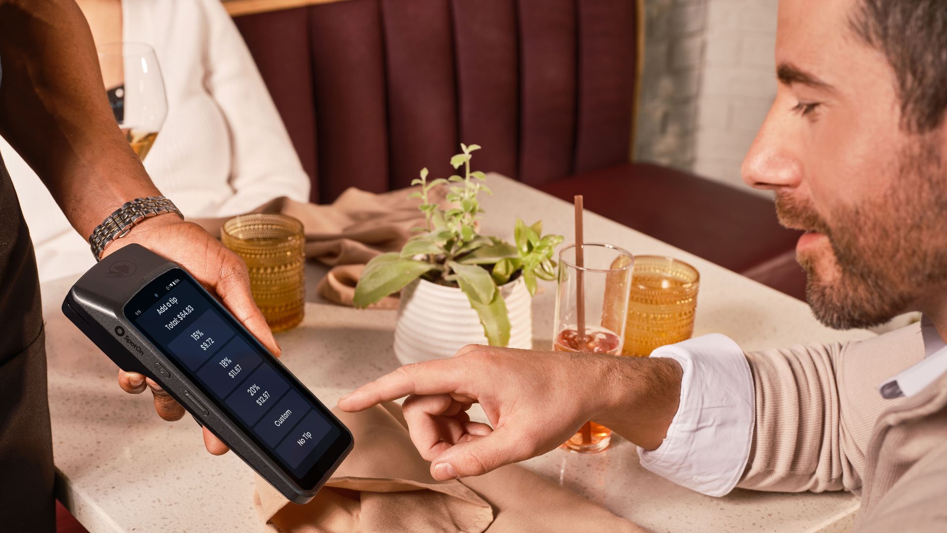 A diner uses a handheld POS system for digital tipping in a casual restaurant setting.
