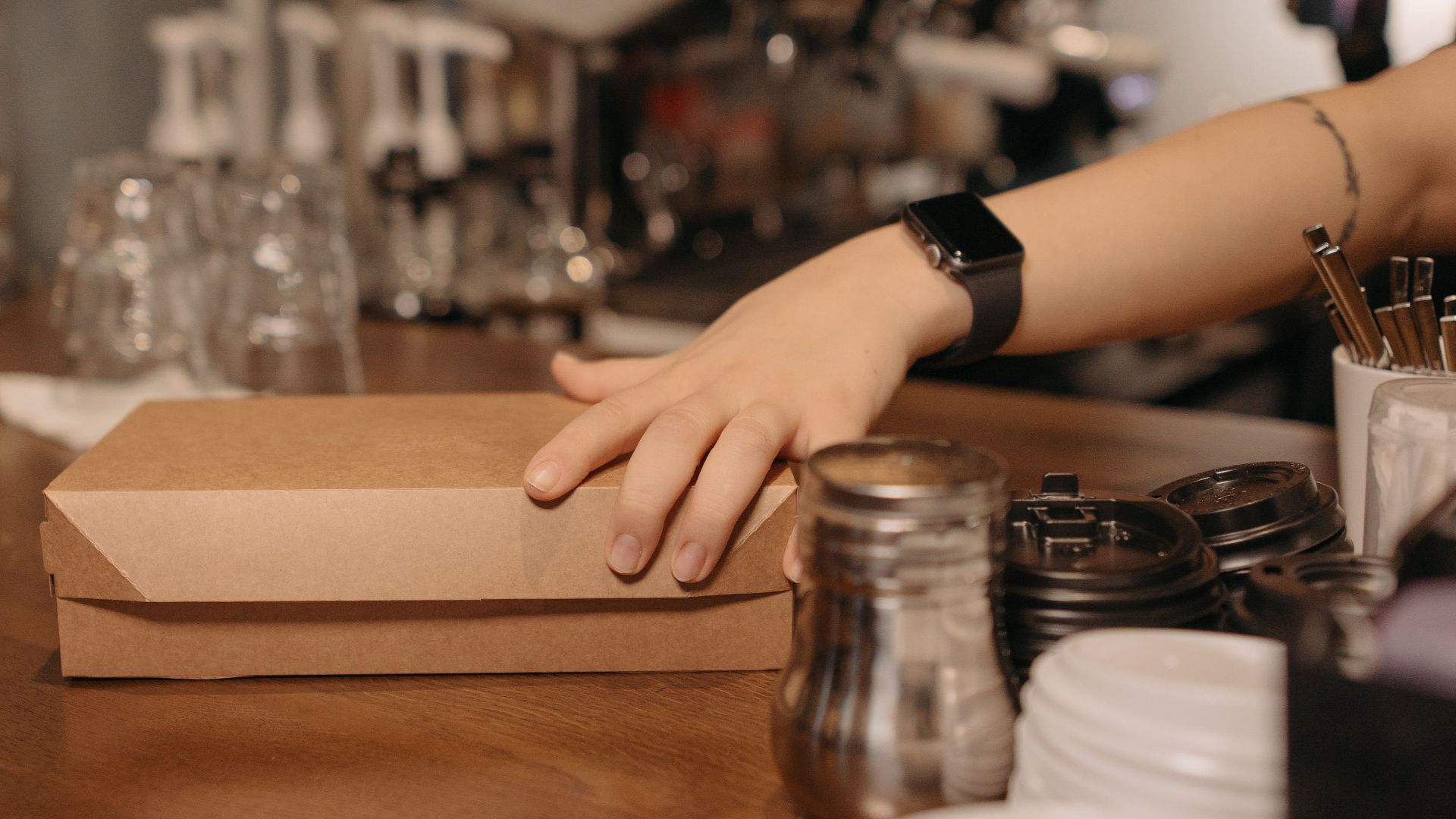 Barista handing over a takeout box at a café counter. Ideal for business and service imagery.