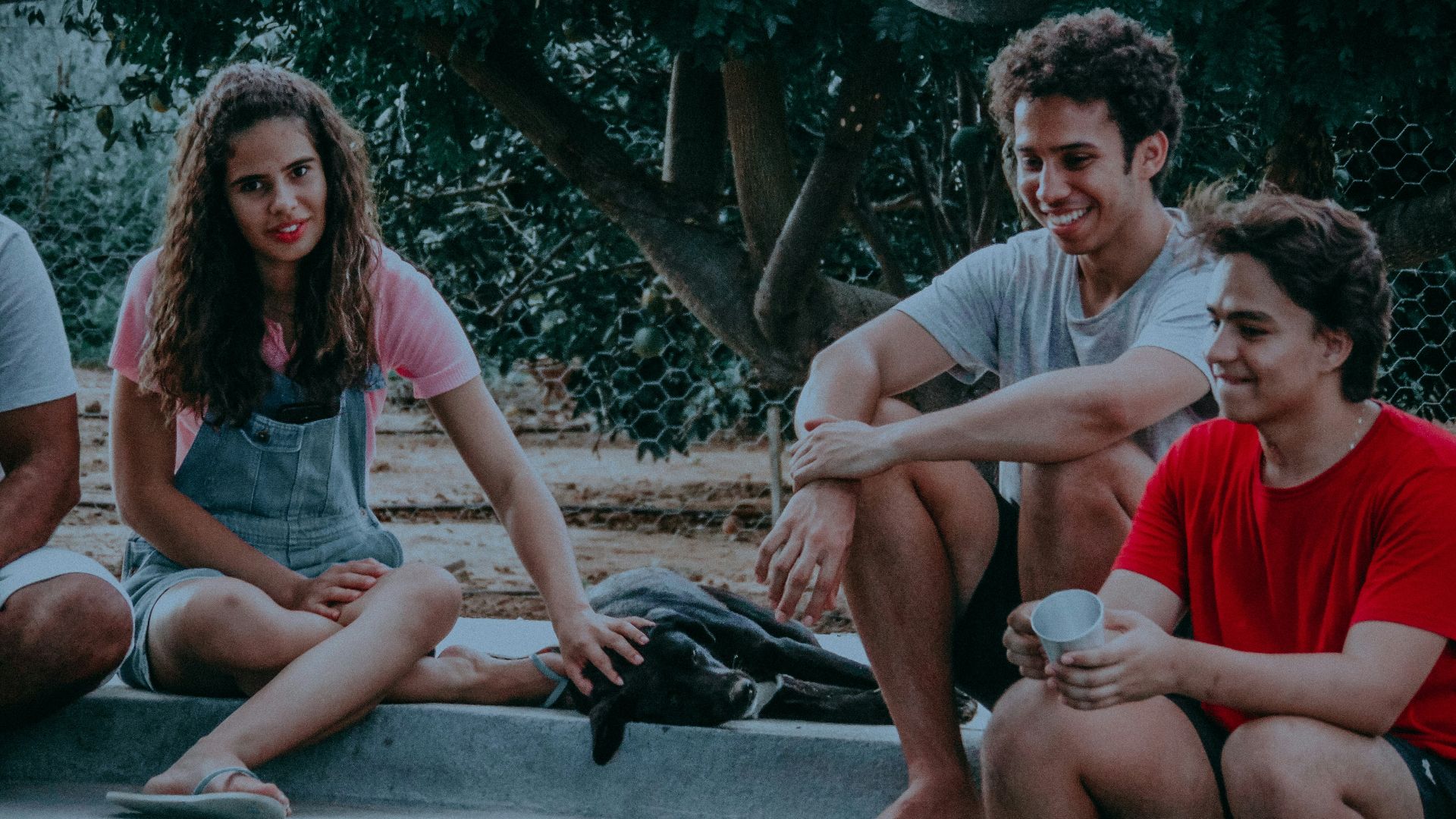 three men and one woman sitting on grey concrete floor