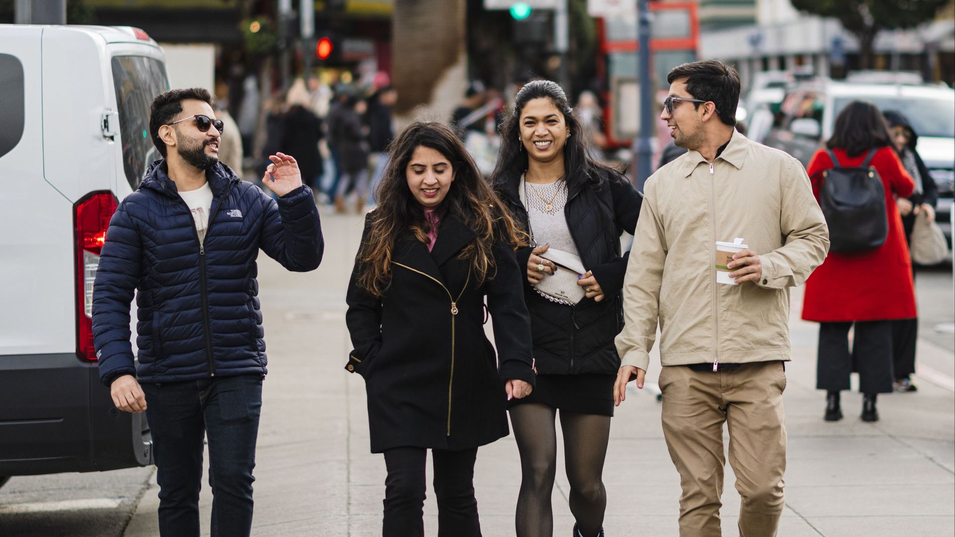 Four friends walking past Fisherman's Wharf sign in San Francisco, enjoying a casual day.