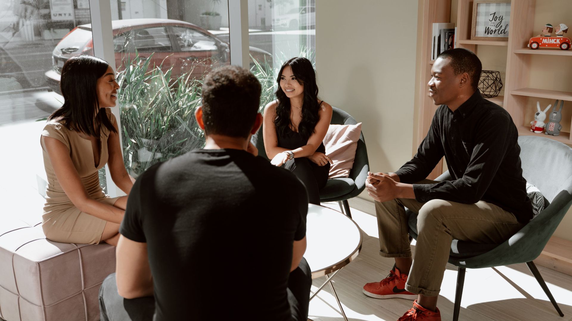 A diverse group of friends engaging in a casual conversation inside a modern coffee shop setting.