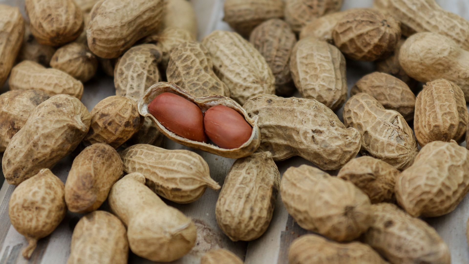 A detailed close-up of peanuts in their shells scattered on a wooden surface.