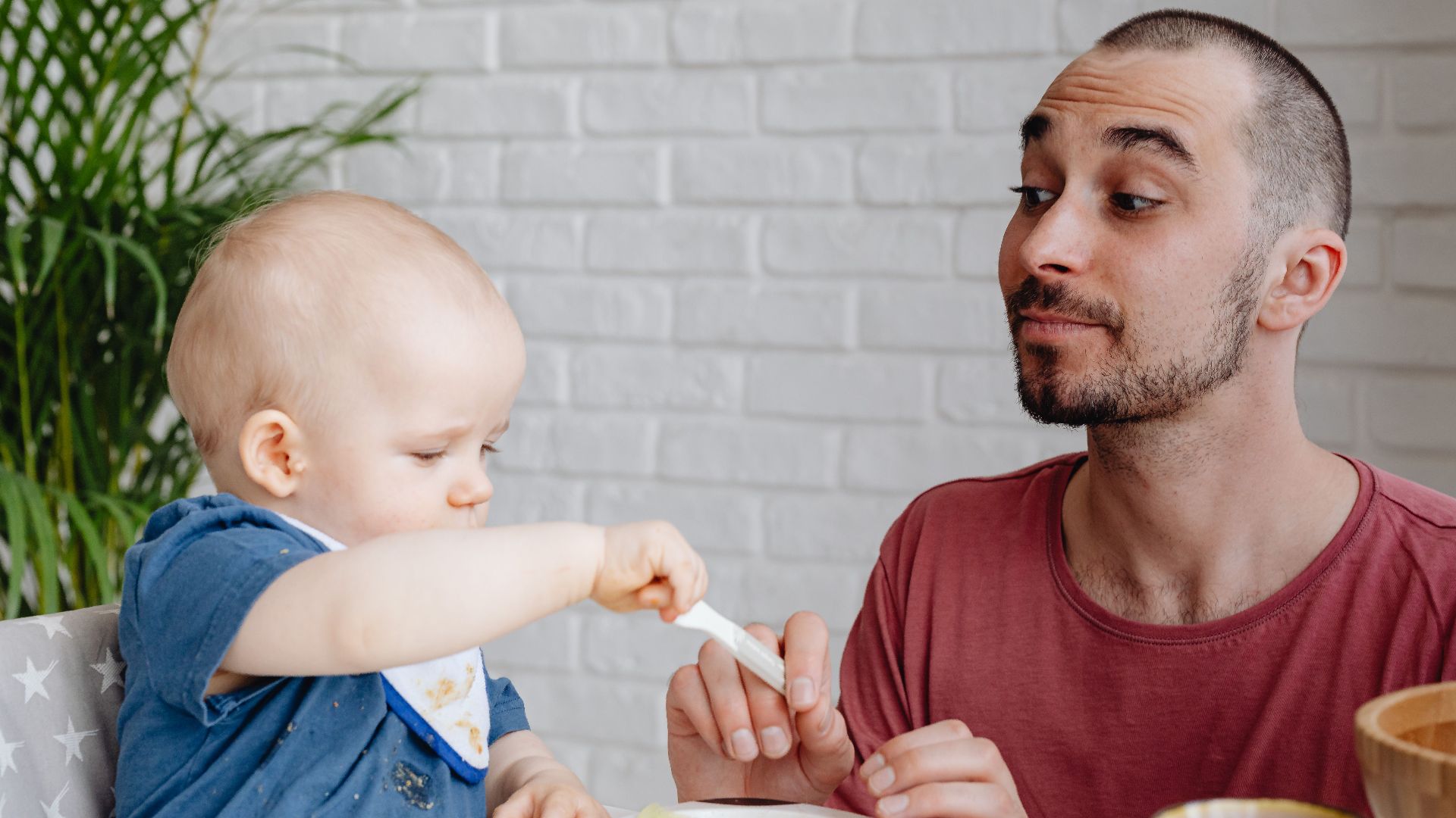 Father and baby enjoying a playful mealtime together at home.