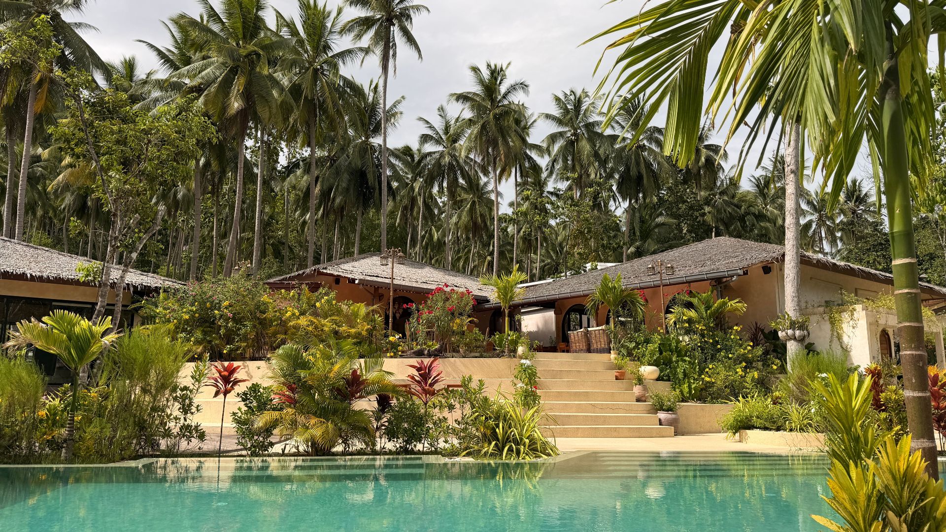 Luxurious tropical resort with palm trees and a swimming pool in Surat Thani, Thailand.