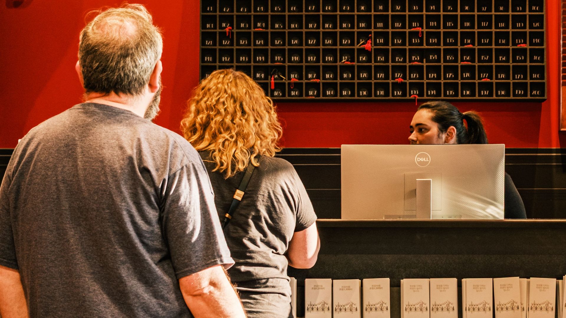 A couple with a dog checks in at a stylish, vintage hotel front desk.