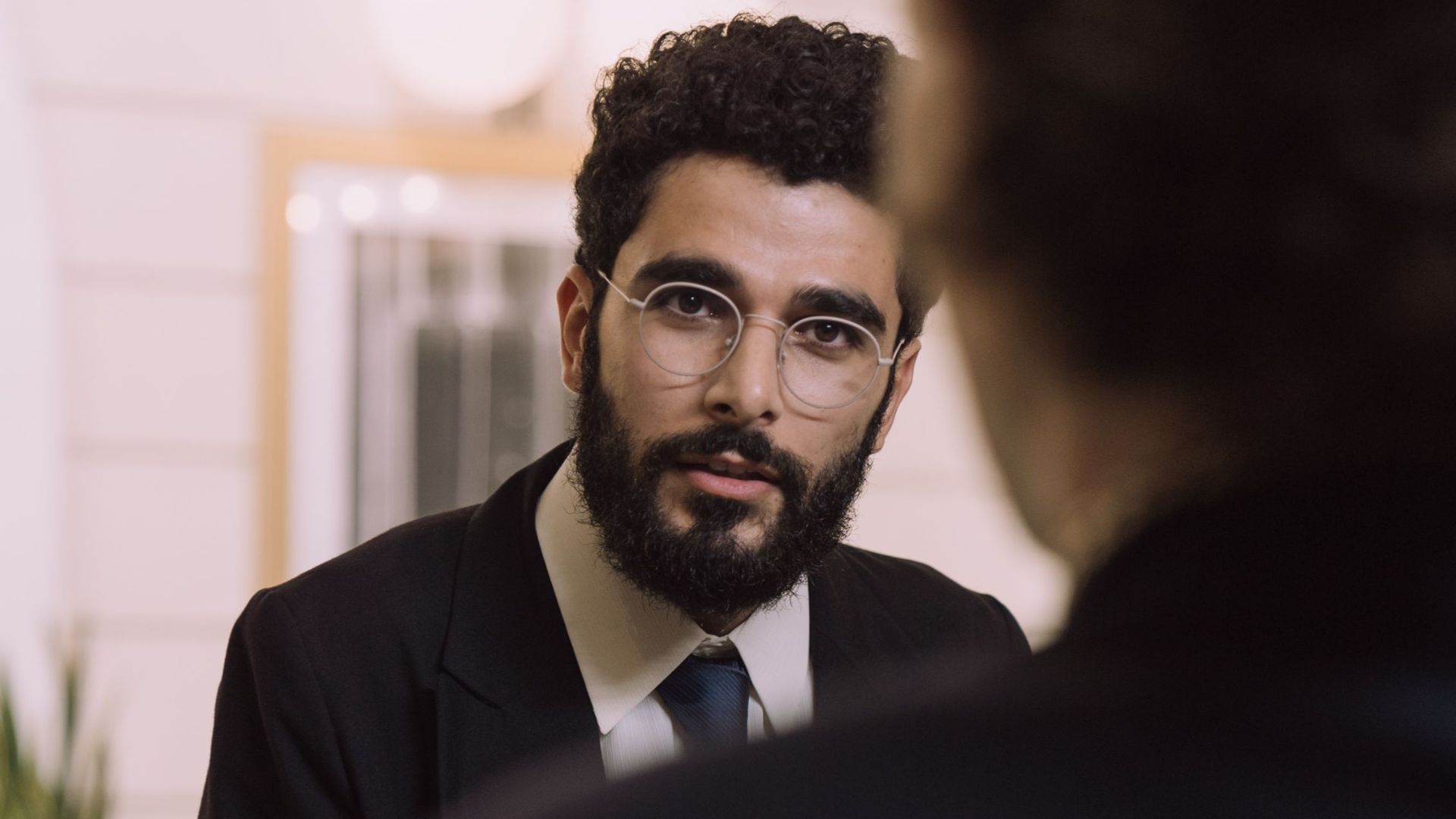 A professional businessman checks in at a hotel reception, engaging with a concierge.