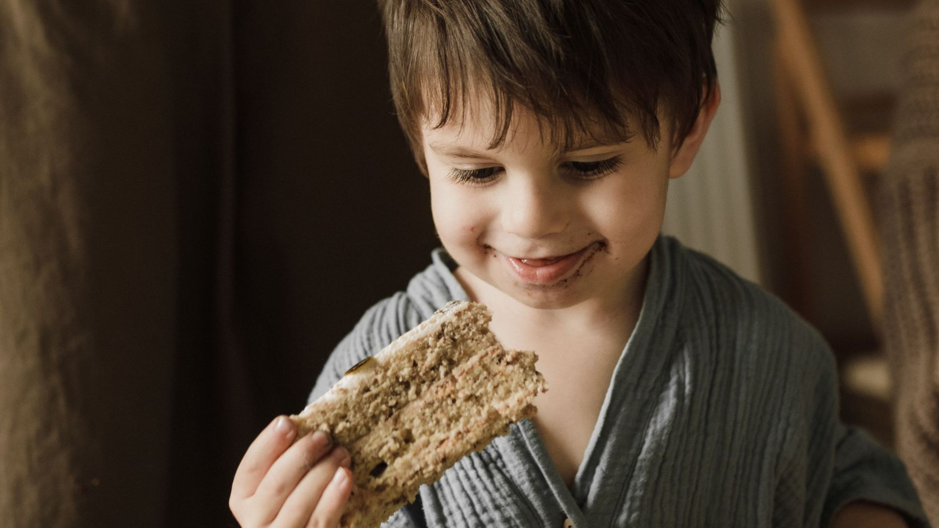 Happy child enjoying a piece of cake at a cozy family gathering indoors.
