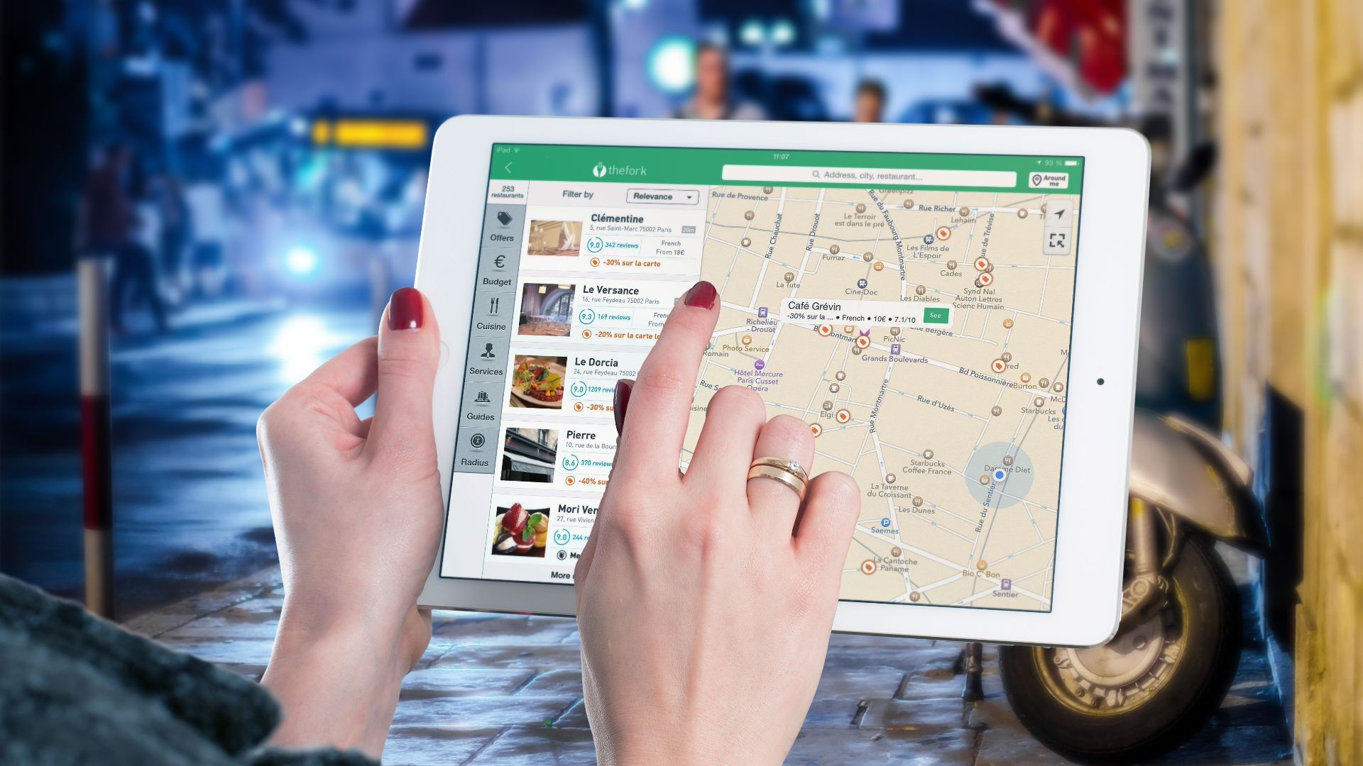 Hands using a digital map on a tablet in an urban setting at night, illustrating navigation and technology.