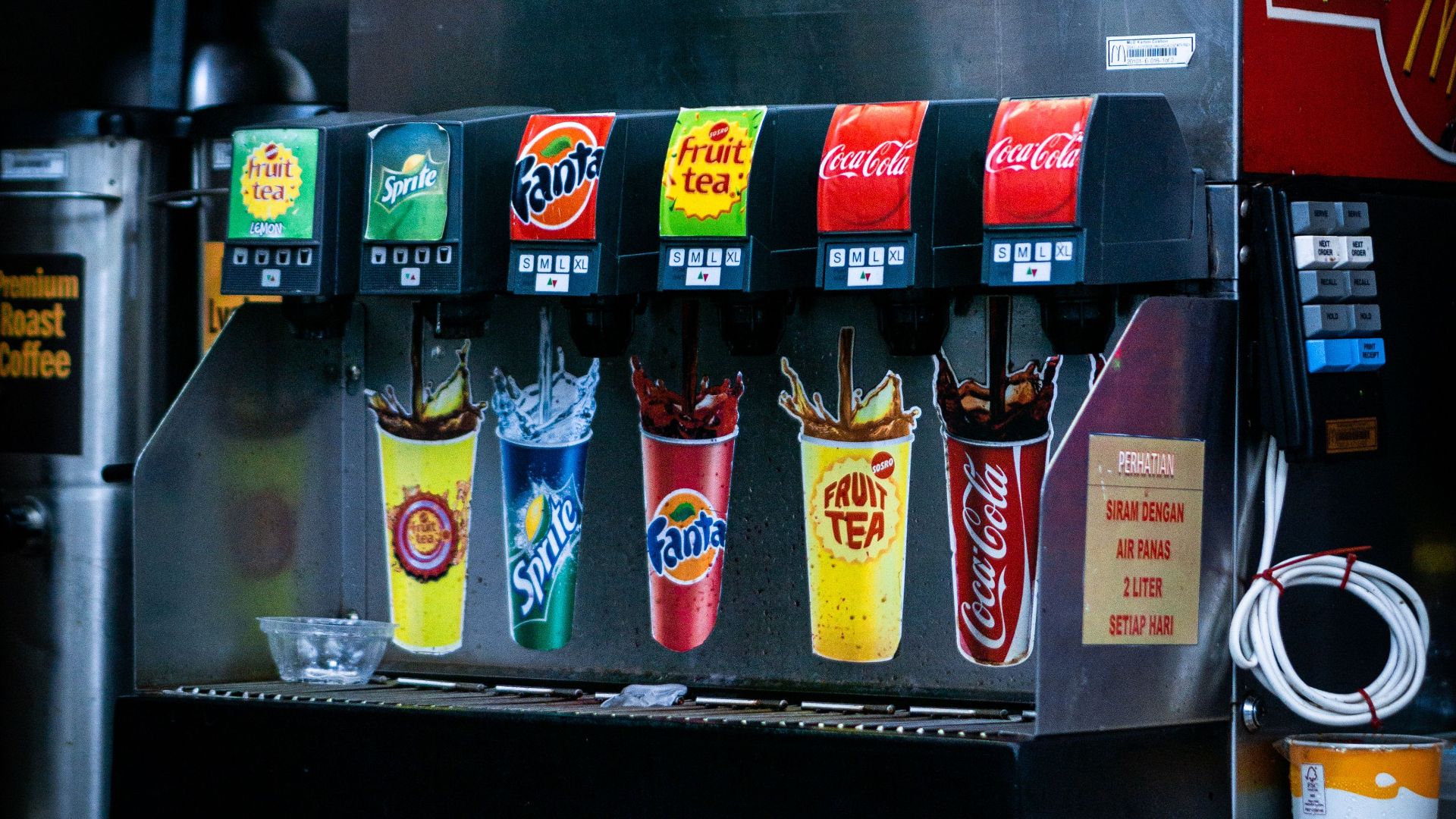 Soft drink dispenser with various soda options in fast food restaurant.