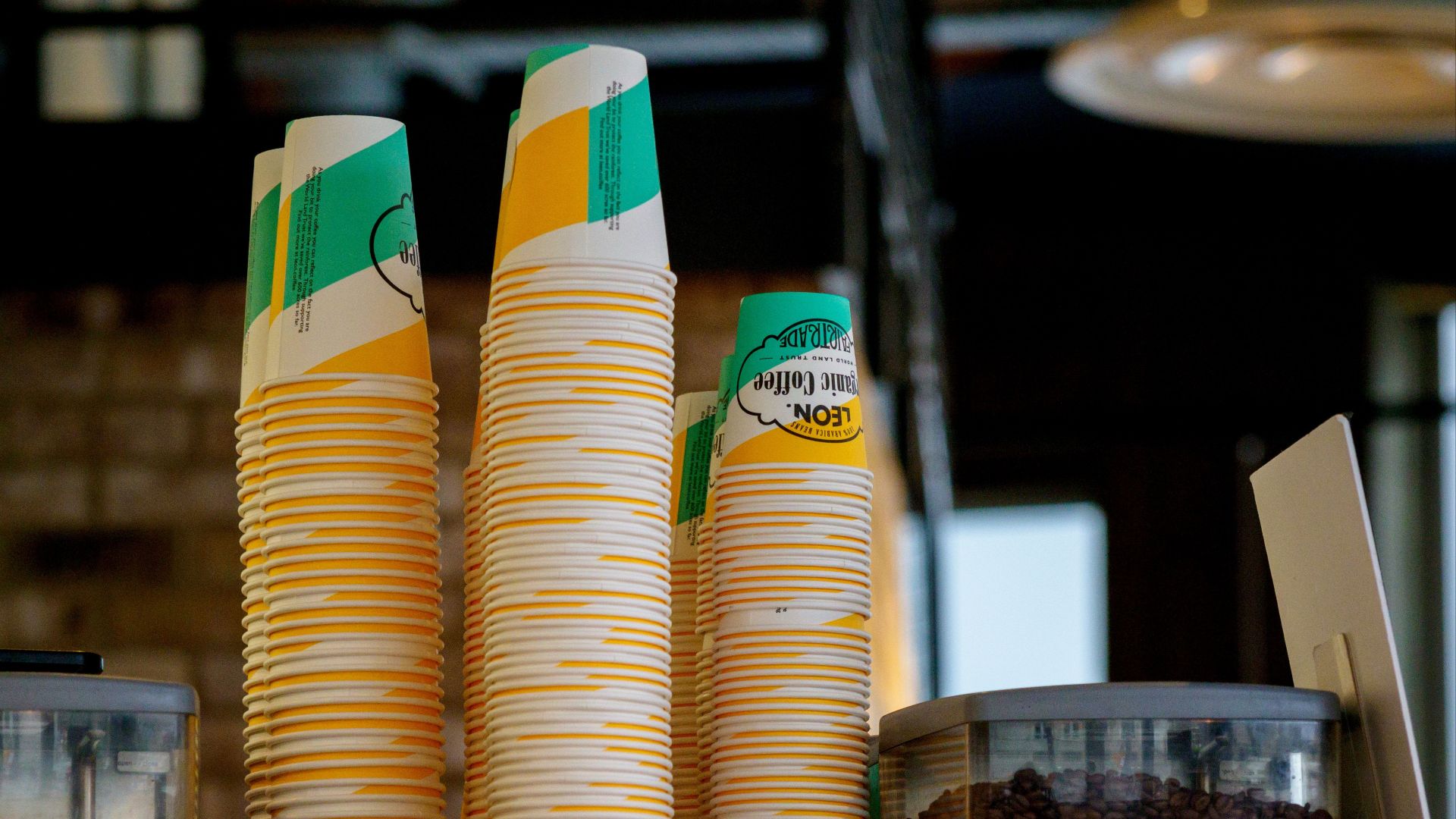 Stacks of colorful paper cups with containers of coffee beans create a cozy café vibe.